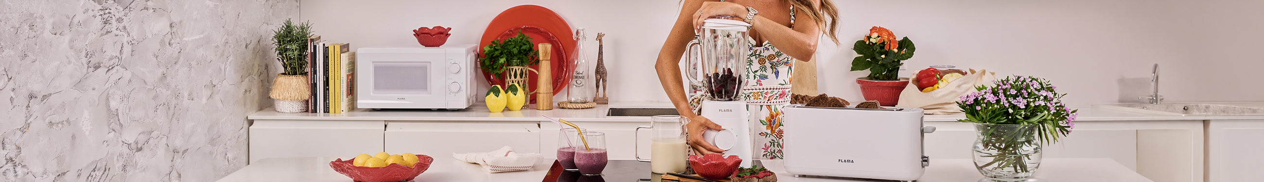 Mulher a usar um liquidificador branco da Flama para preparar um batido saudável numa cozinha decorada
