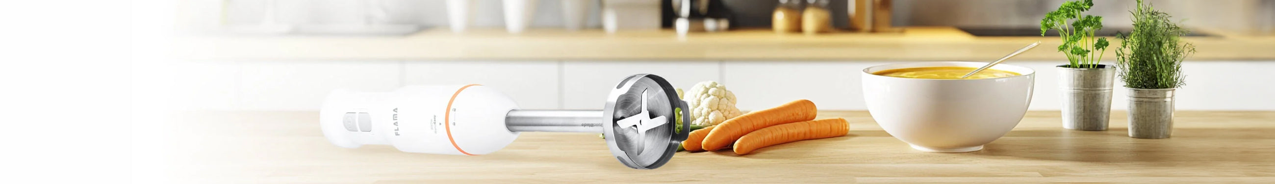 Varinha mágica com pé em inox da Flama numa mesa com cenouras e uma taça de sopa de legumes